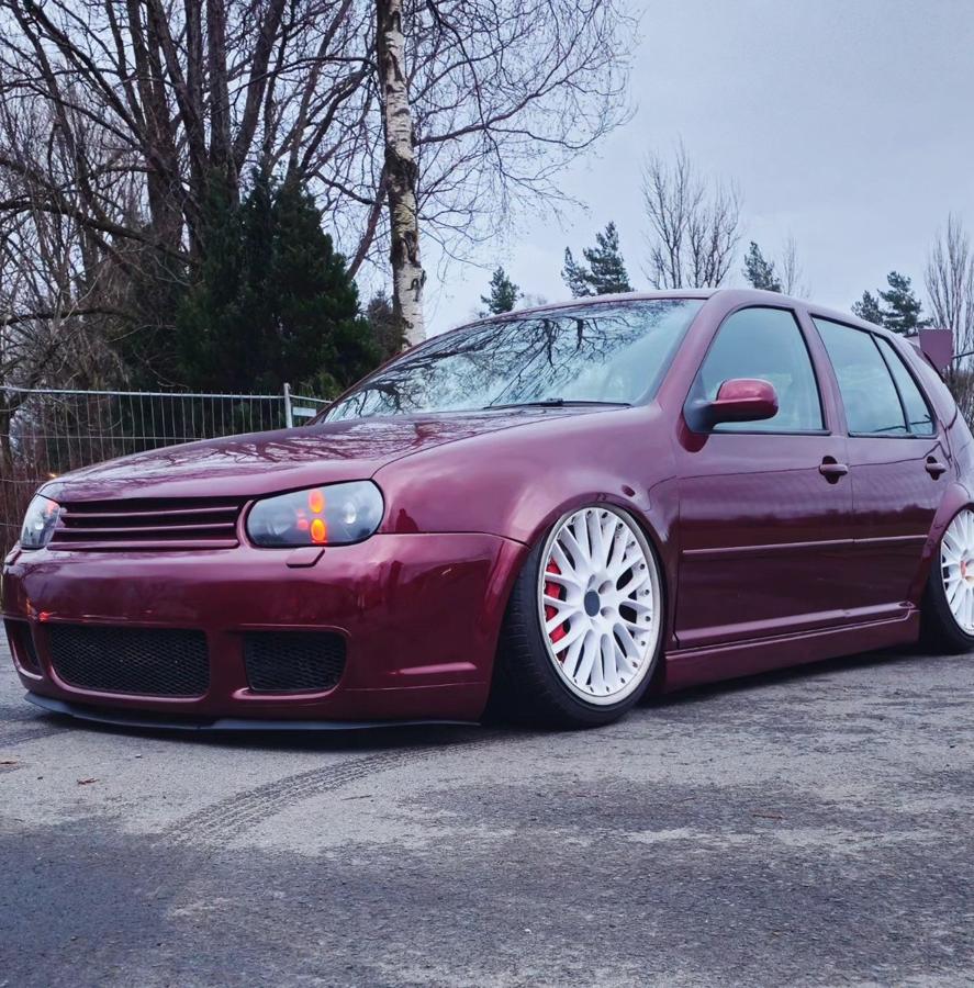A lowered burgundy Volkswagen Golf Mk4 on white multi-spoke wheels